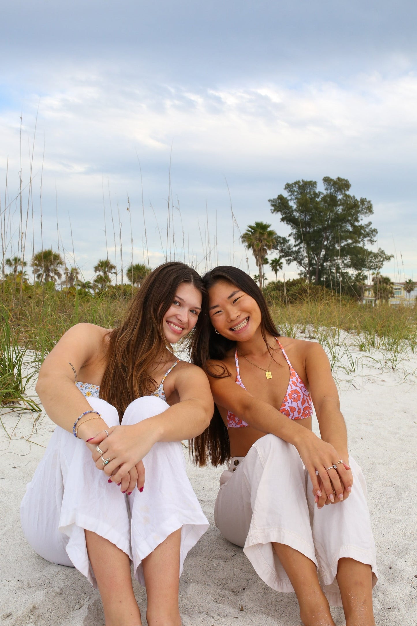 Two models wearing LOKAL floral print bikini tops at the beach. Mystery bag prints and styles vary.